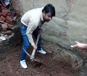 ग्रामीण के घर पर शौचालय के लिए गड्ढ़ा खोदते हुए कपिलदेव
